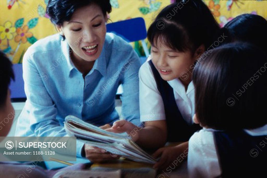 Stock Photo: 1188-1128 Female teacher teaching her students with a book