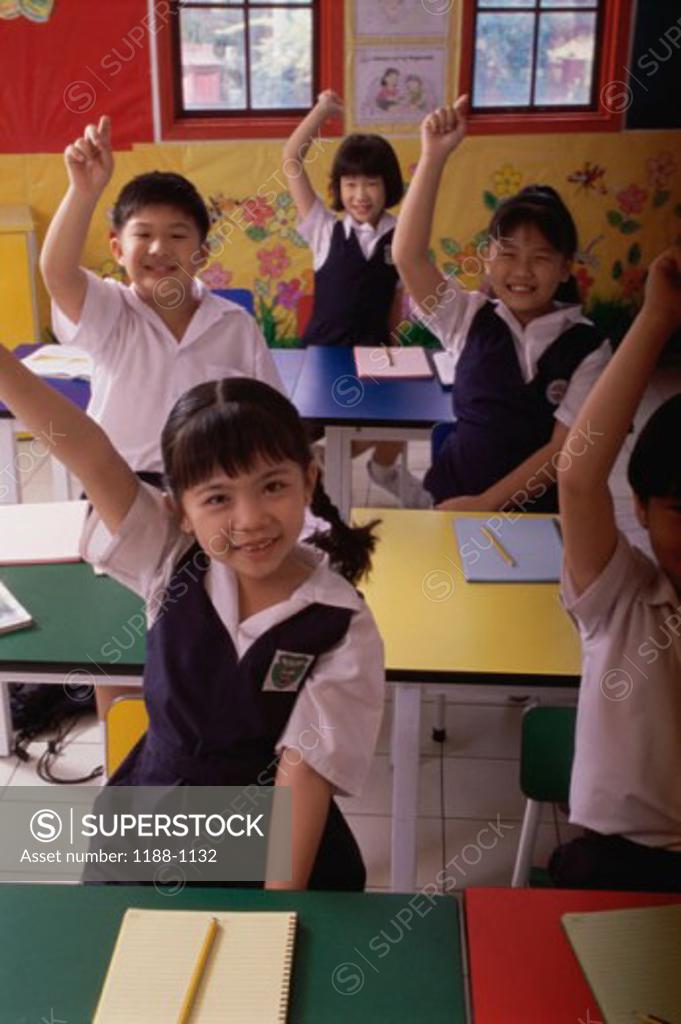 Stock Photo: 1188-1132 Group of children raising their hands in a classroom