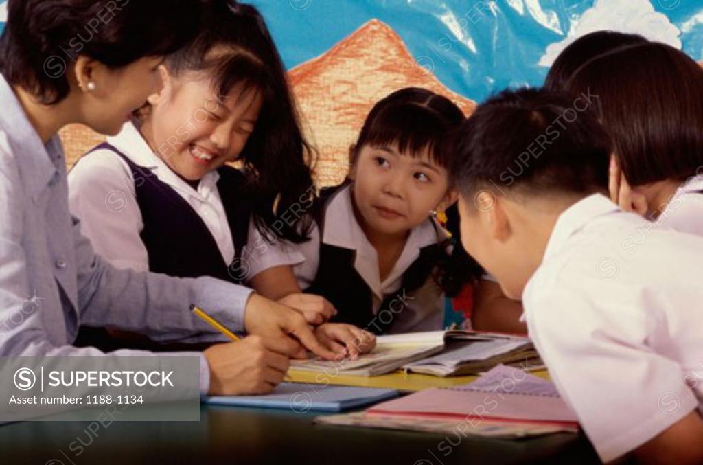 Stock Photo: 1188-1134 Teacher sitting with her students in a classroom