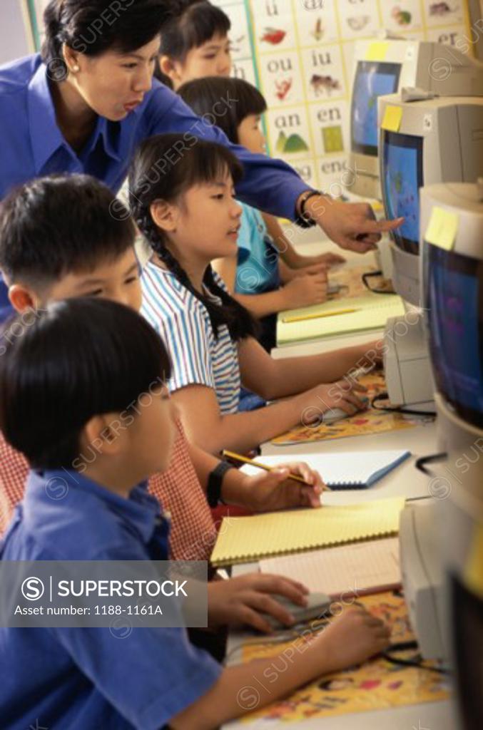 Stock Photo: 1188-1161A Female teacher with her students in front of computers