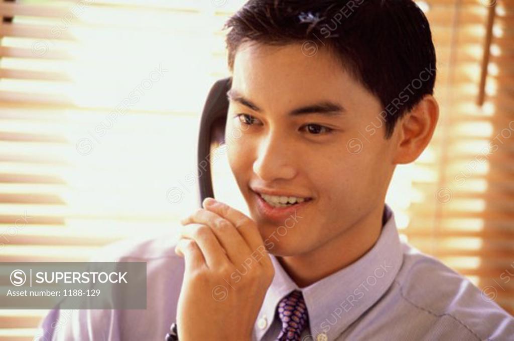 Stock Photo: 1188-129 Close-up of a young businessman using the landline telephone at his desk