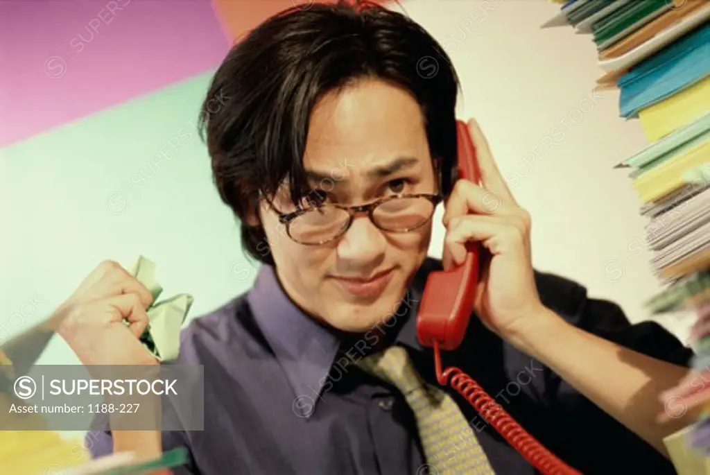 Close-up of a young businessman using a landline telephone in the office