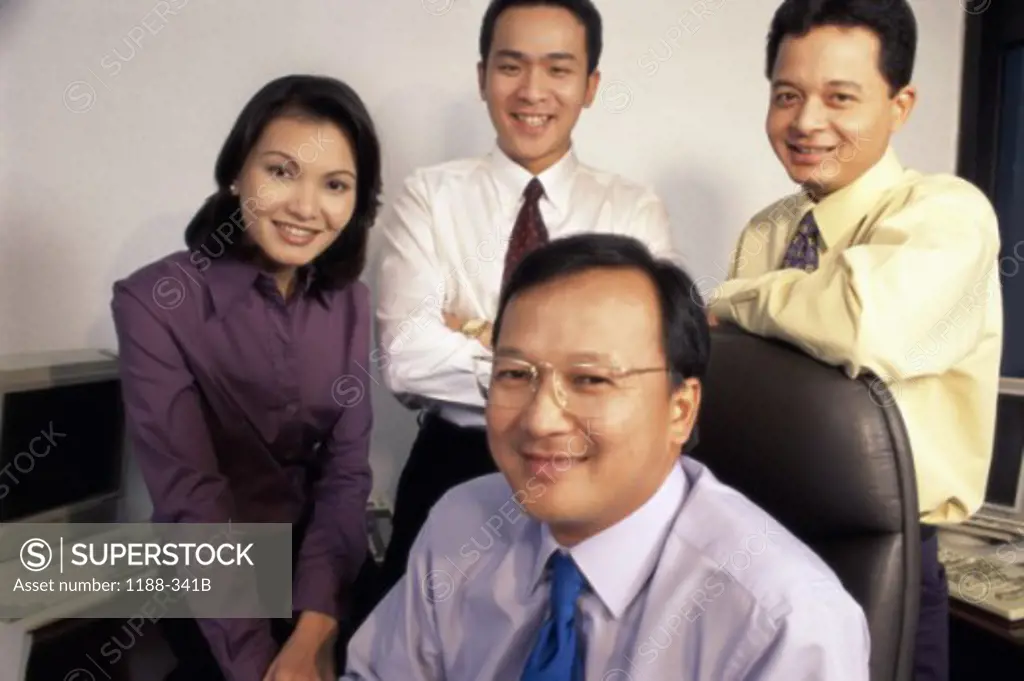 Portrait of three businessmen and a businesswoman smiling in an office
