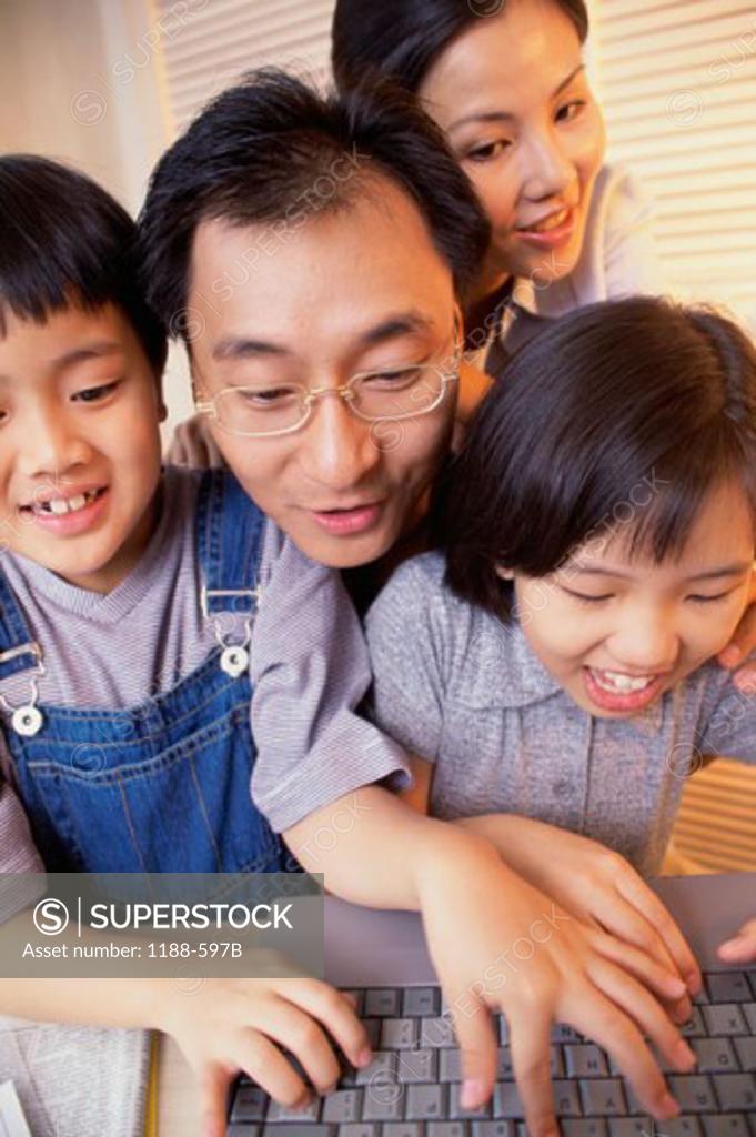 Stock Photo: 1188-597B Mid adult couple with their son and daughter using a laptop