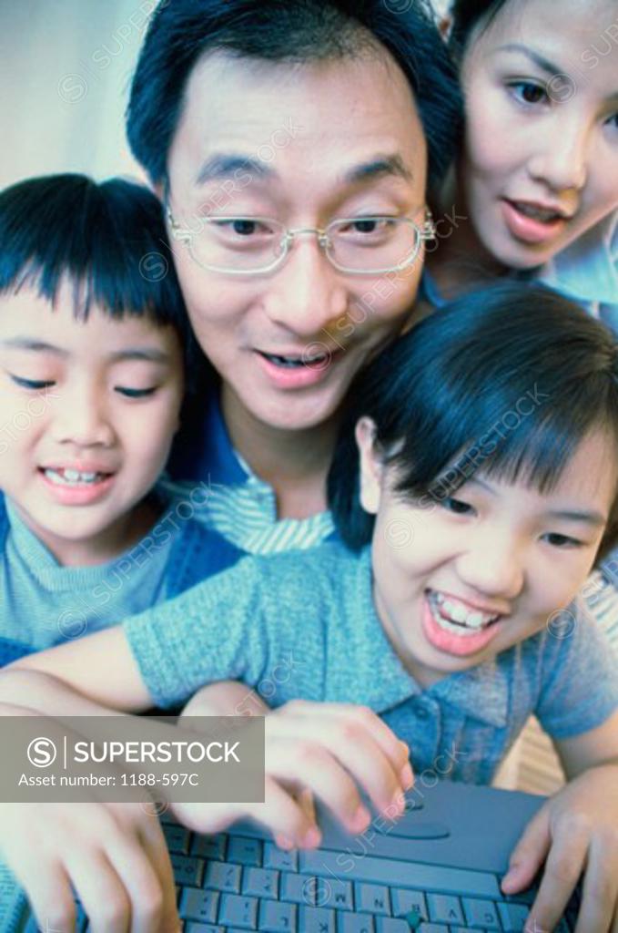 Stock Photo: 1188-597C Mid adult couple with their son and daughter using a laptop