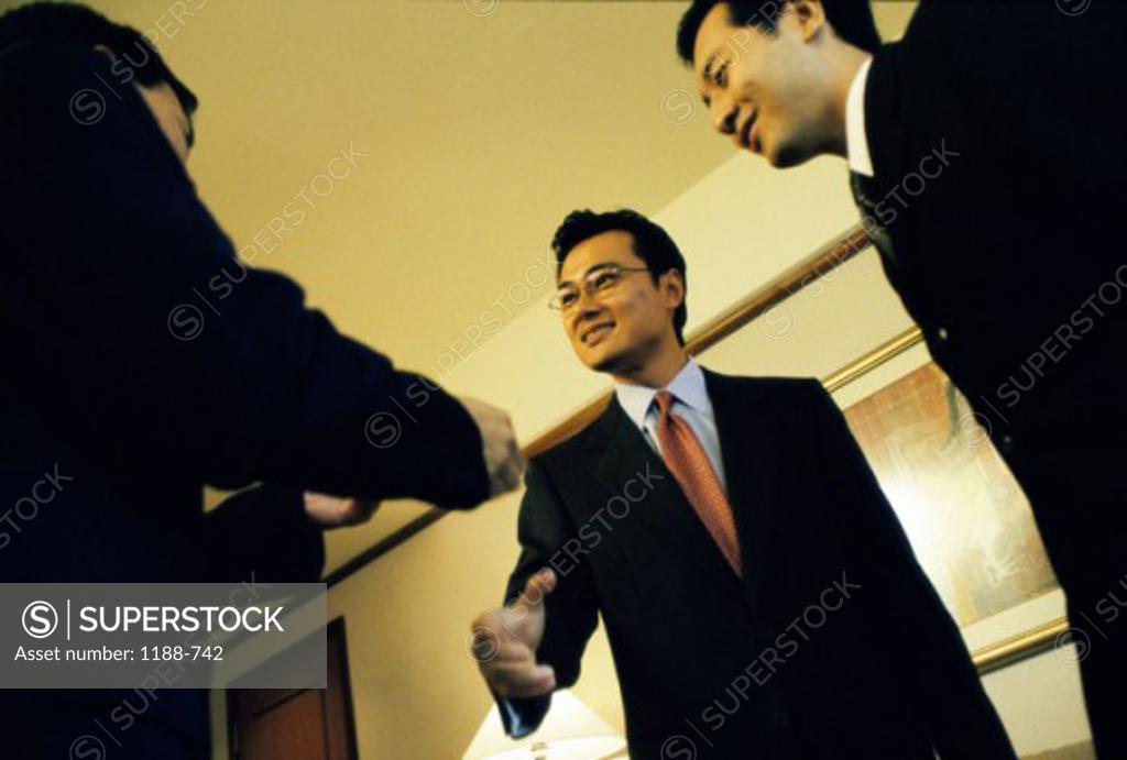 Stock Photo: 1188-742 Low angle view of three businessmen shaking hands in an office
