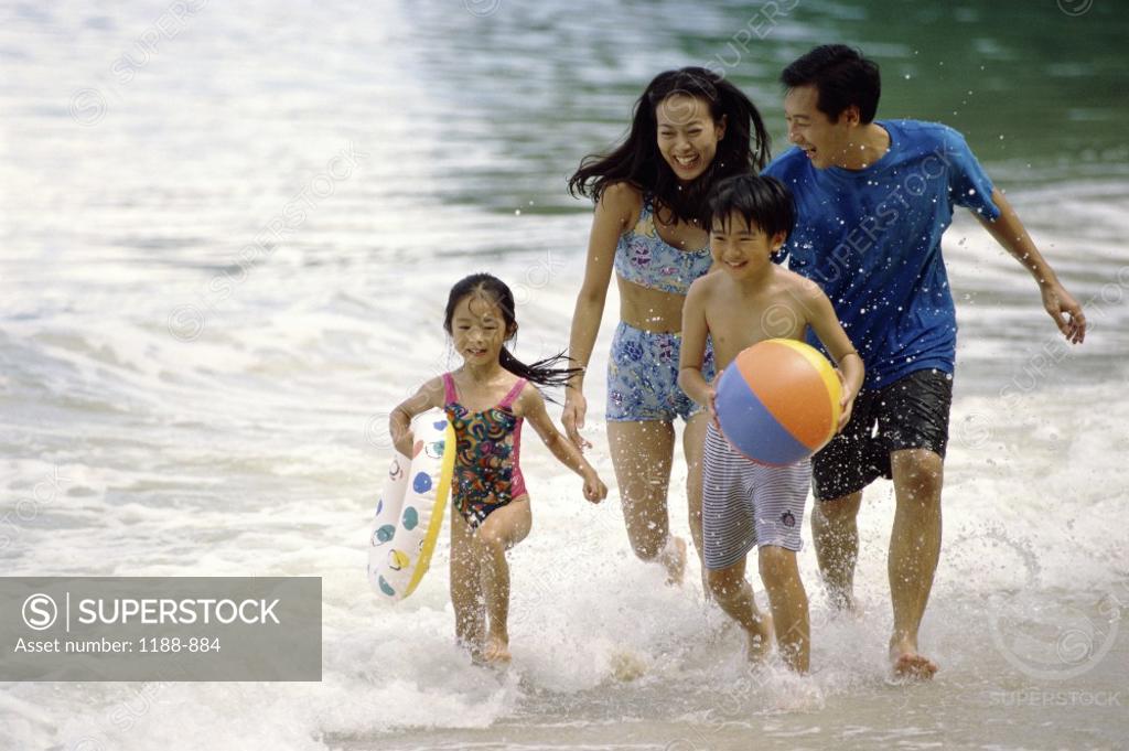 Stock Photo: 1188-884 Young couple running on the beach with their son and daughter
