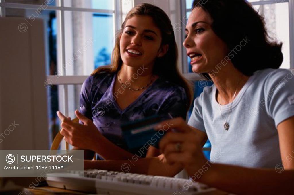 Stock Photo: 1189-1116A Mother with her daughter using a computer and holding a credit card