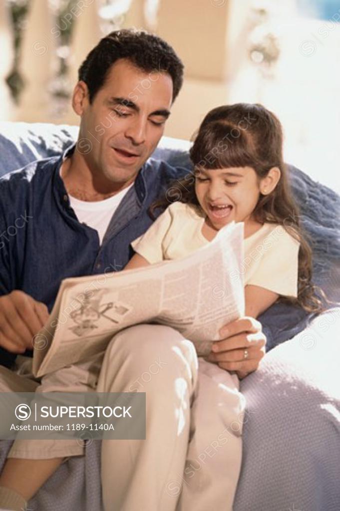 Stock Photo: 1189-1140A Close-up of a mid adult man with his daughter reading a newspaper