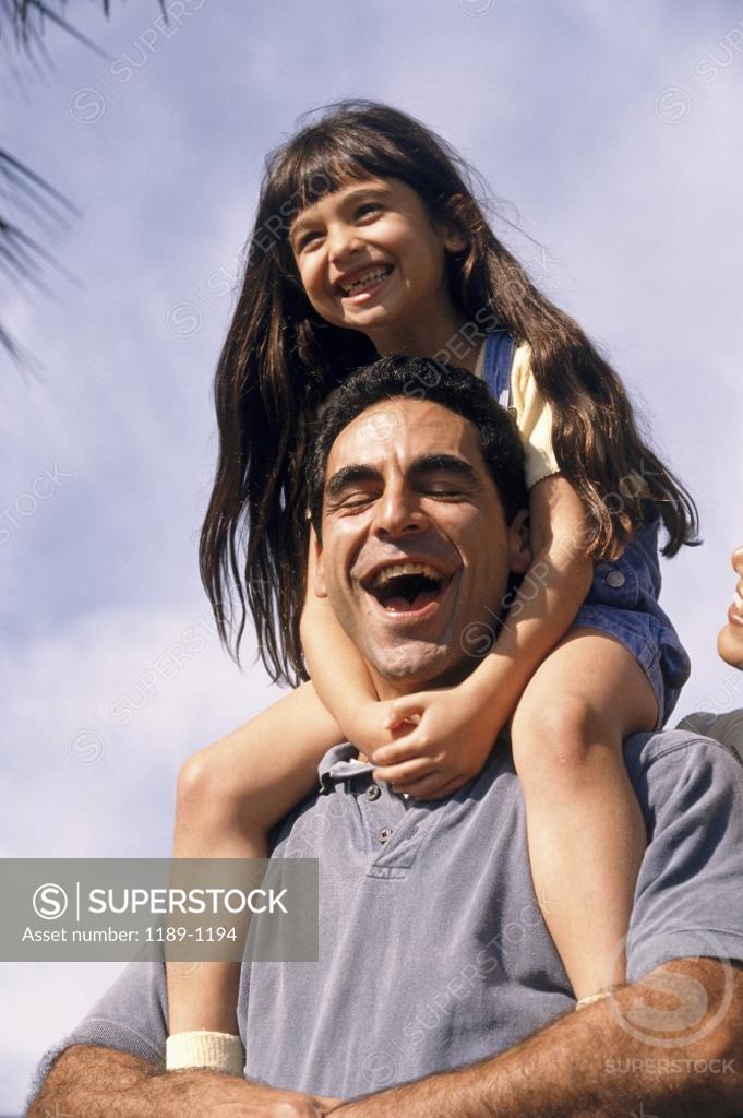Stock Photo: 1189-1194 Low angle view of a mid adult man carrying his daughter on his shoulders