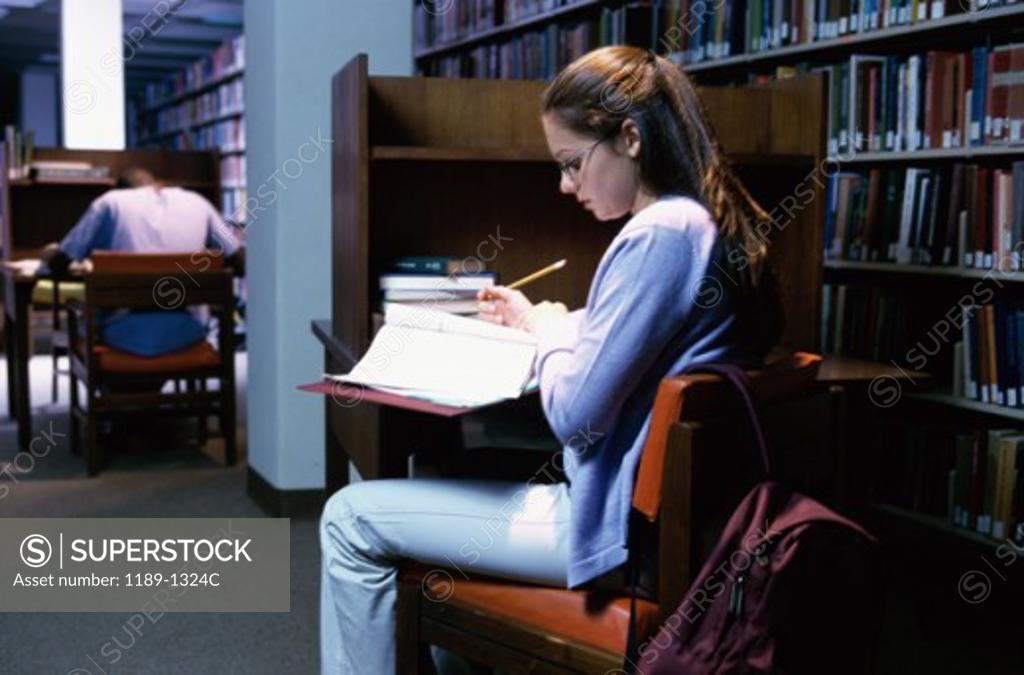 Stock Photo: 1189-1324C Side profile of a teenage girl reading a book in a library