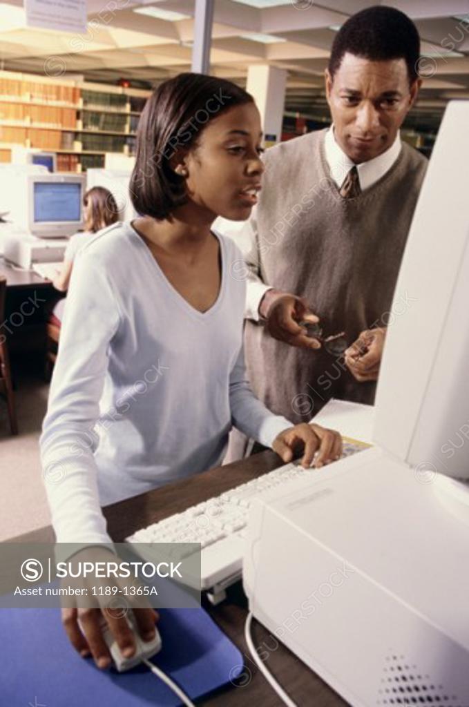 Stock Photo: 1189-1365A Male teacher and a teenage girl in front of a computer
