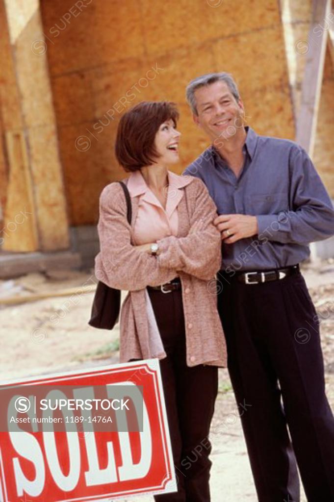 Stock Photo: 1189-1476A Mature couple standing in front of a new house