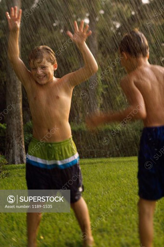 Stock Photo: 1189-1535 Two boys playing in a water sprinkler on a lawn