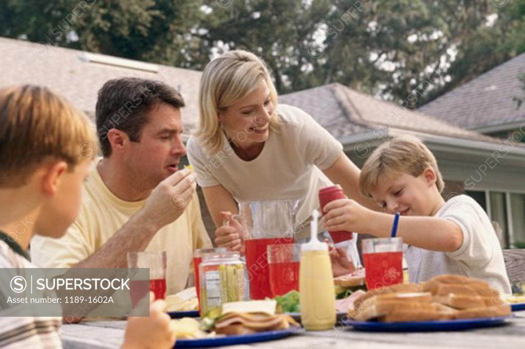 Stock Photo: 1189-1602A Mid adult woman serving food to her husband and two sons