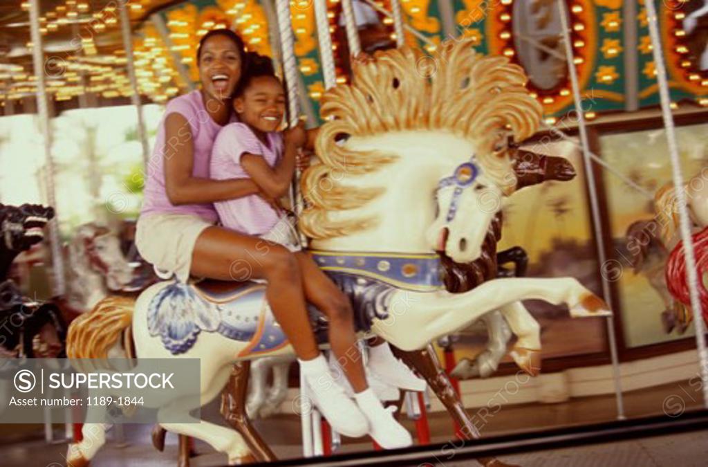 Stock Photo: 1189-1844 Portrait of a mother and daughter riding on a carousel horse