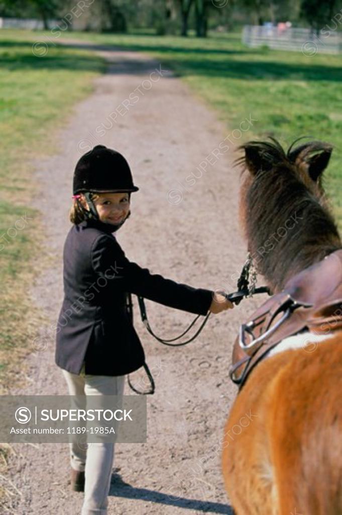 Stock Photo: 1189-1985A Portrait of a girl holding the reins of a pony