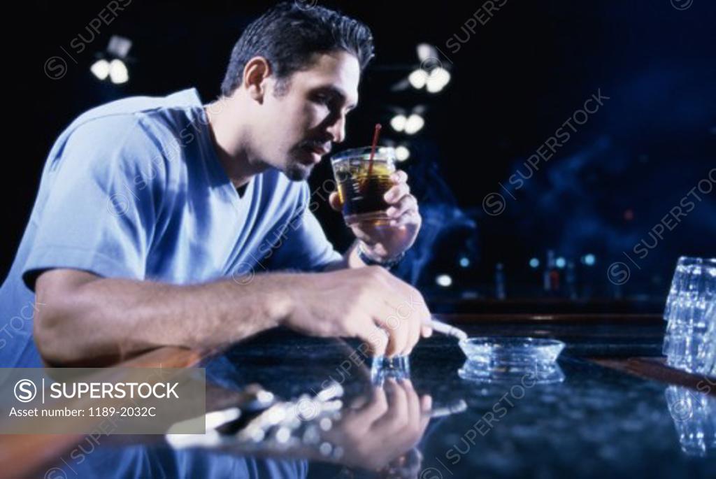 Stock Photo: 1189-2032C Young man smoking a cigarette and drinking alcohol