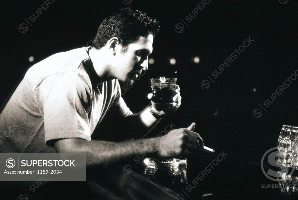 Stock Photo: 1189-2034 Side profile of a young man drinking and smoking