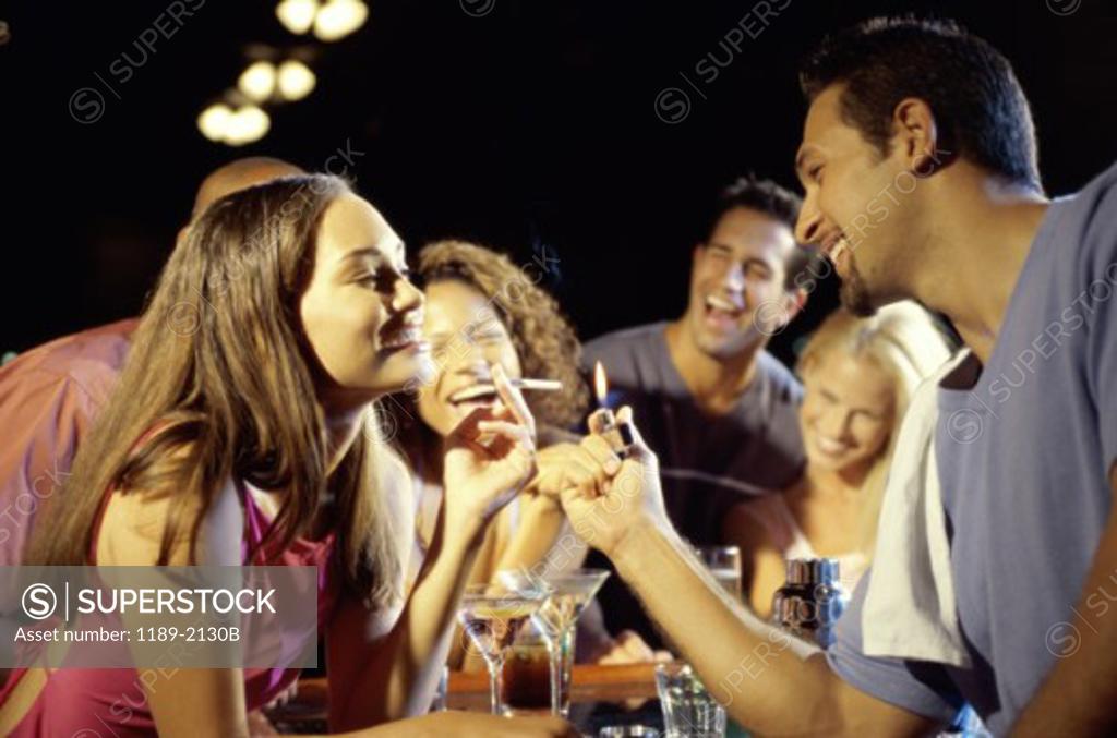 Stock Photo: 1189-2130B Young man lighting a young woman's cigarette