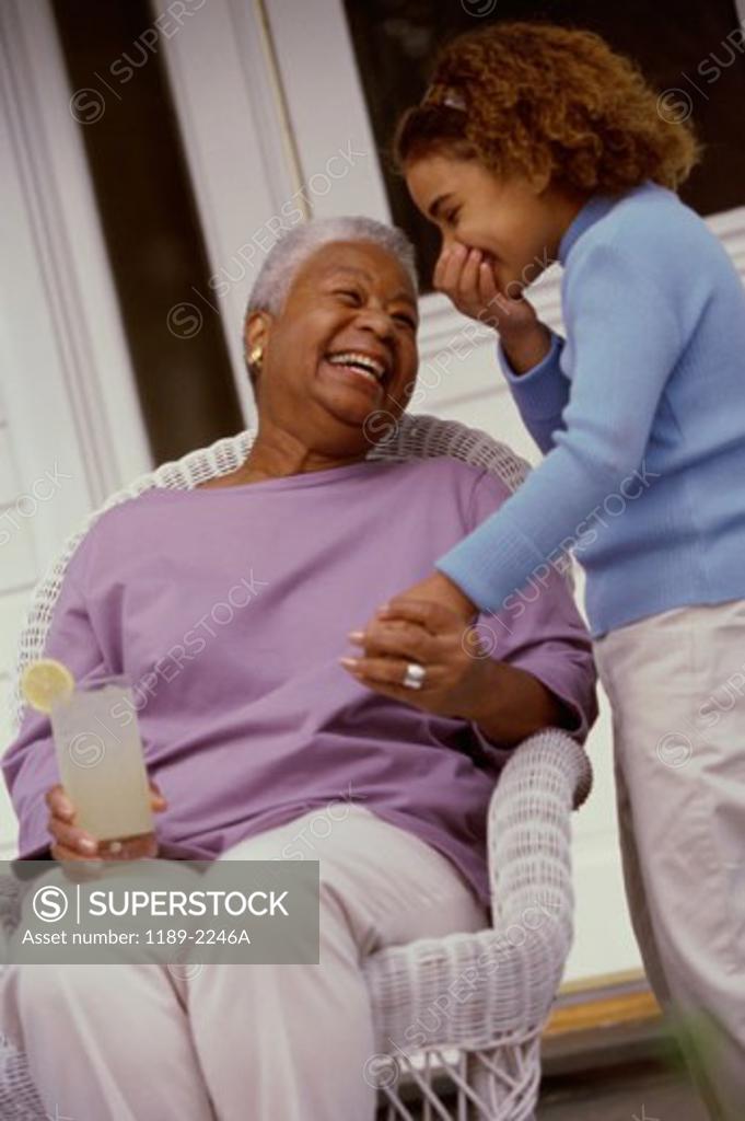 Stock Photo: 1189-2246A Grandmother holding a glass of lemonade with her granddaughter standing beside her