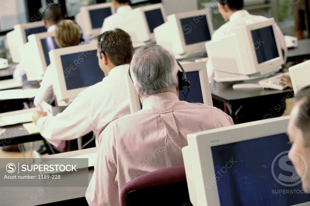 Stock Photo: 1189-228 Rear view of business executives wearing headsets working on computers