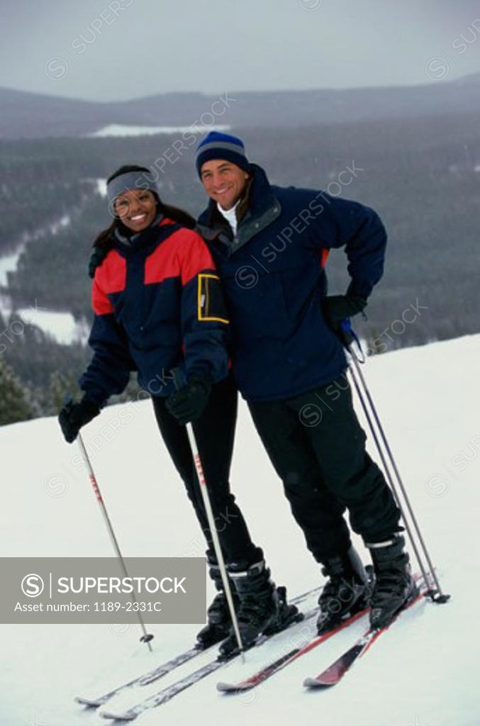 Stock Photo: 1189-2331C Portrait of a young couple standing in snow with ski equipment