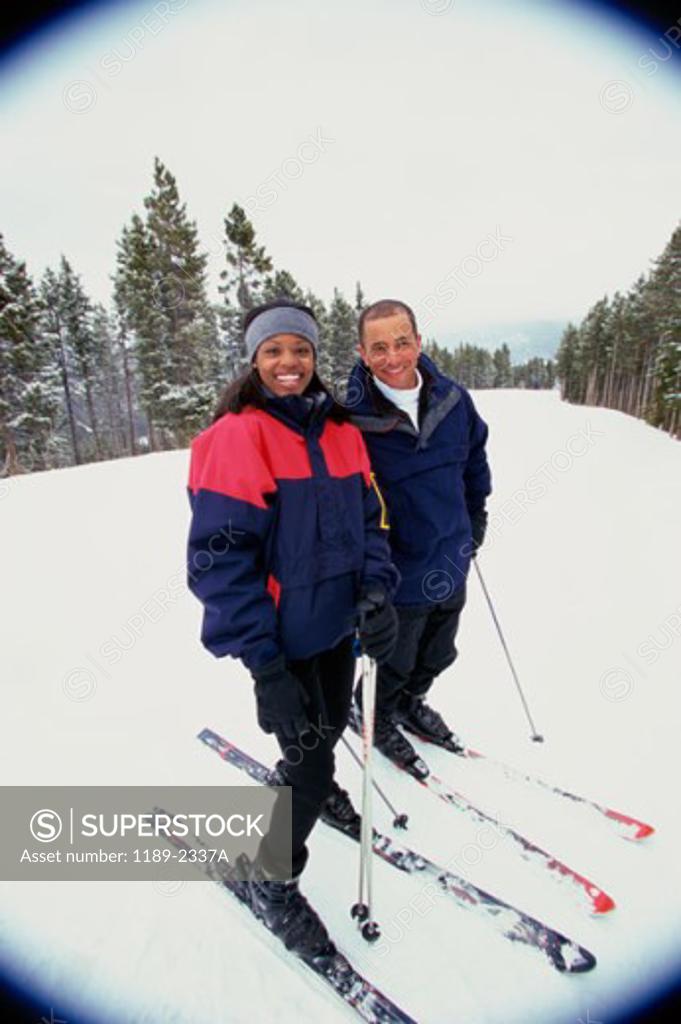 Stock Photo: 1189-2337A Portrait of a young couple standing in snow with ski equipment