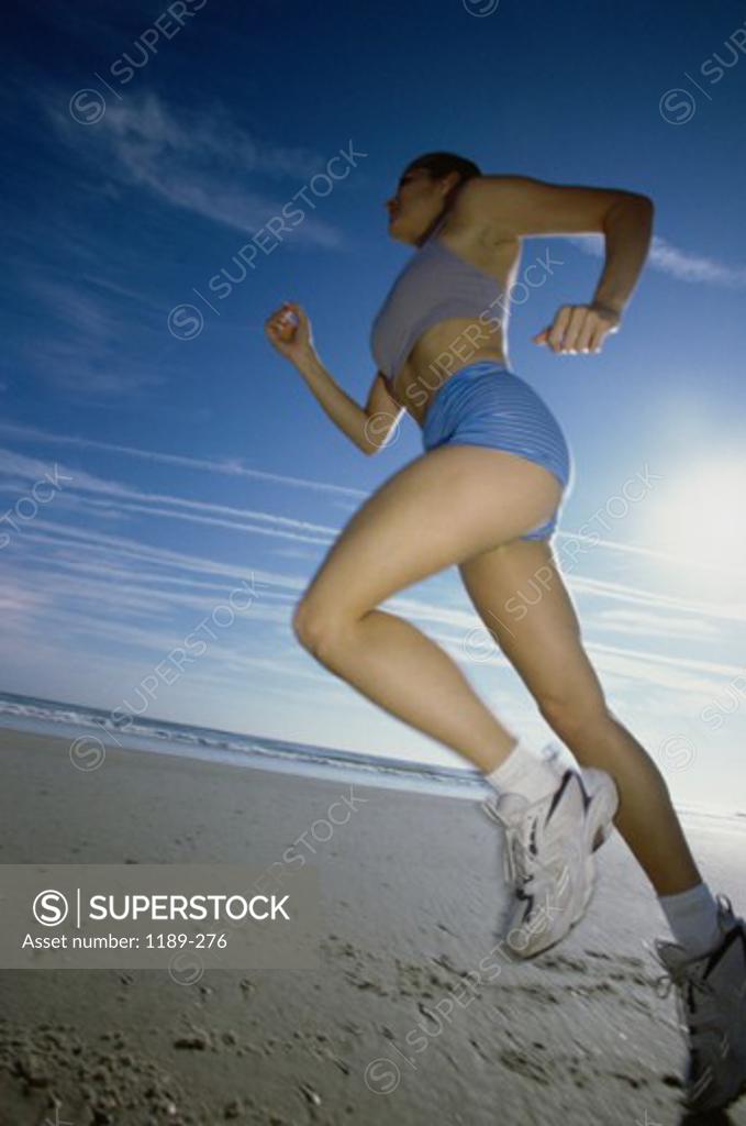 Stock Photo: 1189-276 Low angle view of a young woman jogging on the beach