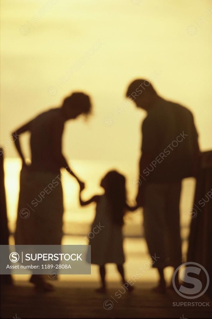 Stock Photo: 1189-2808A Silhouette of a young couple with their daughter on the beach