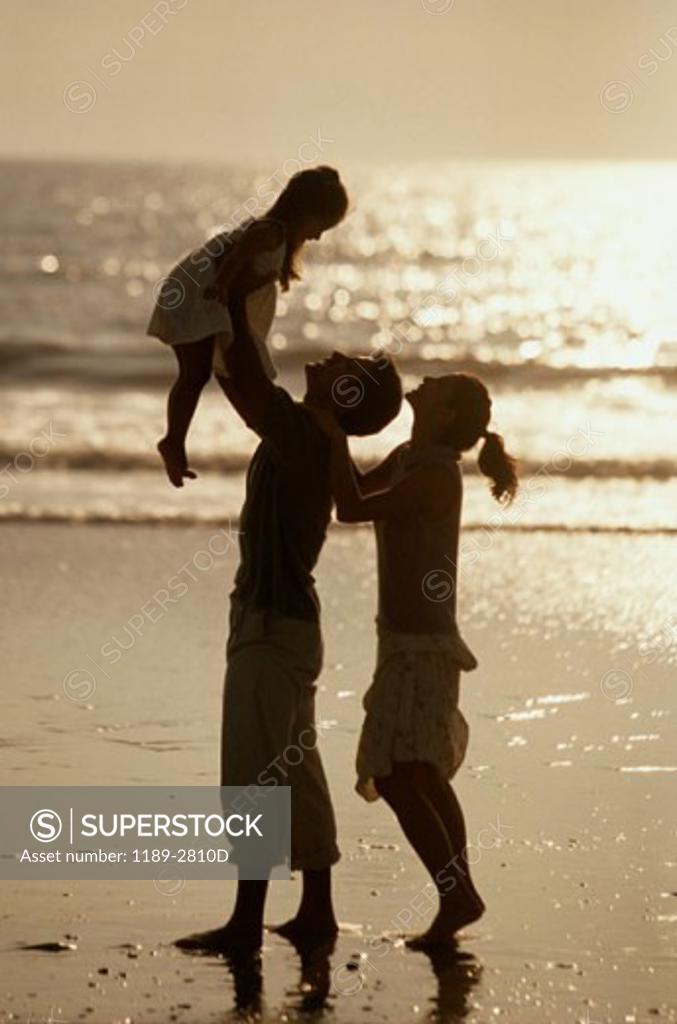 Stock Photo: 1189-2810D Silhouette of a young couple with their daughter on the beach