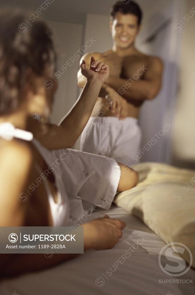Stock Photo: 1189-2828A Young woman lying in bed and gesturing to a young man