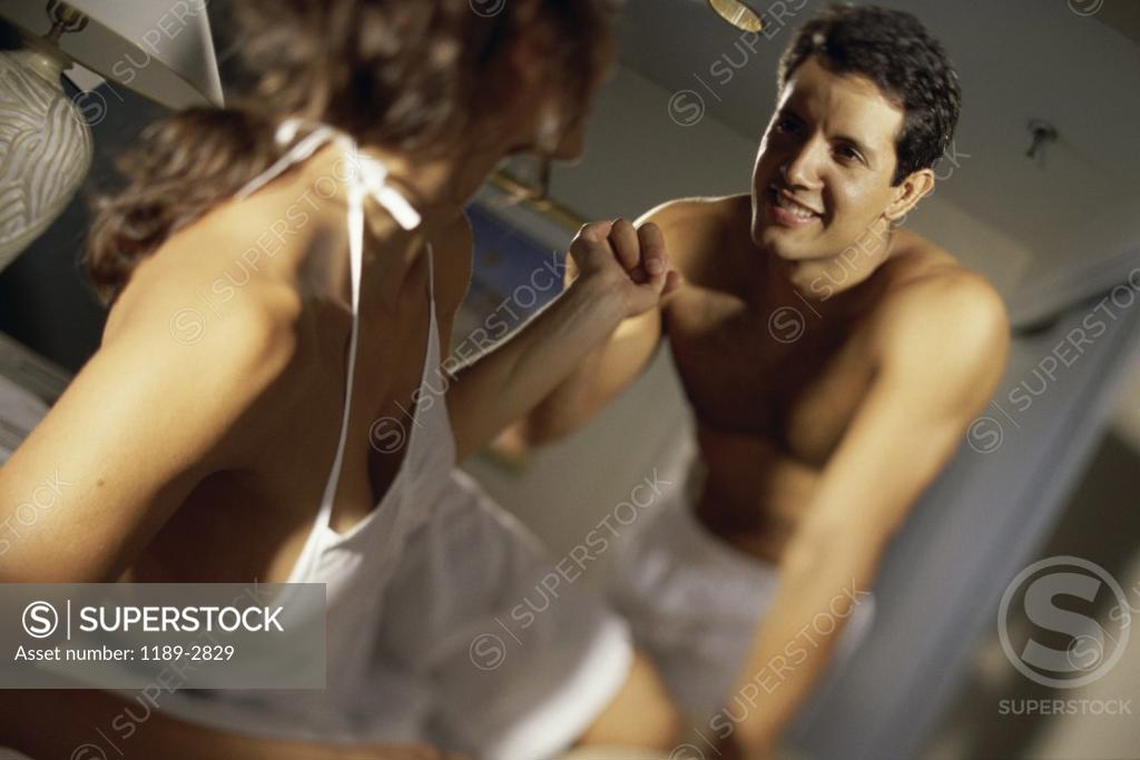 Stock Photo: 1189-2829 Young woman lying in bed holding a young man's hand