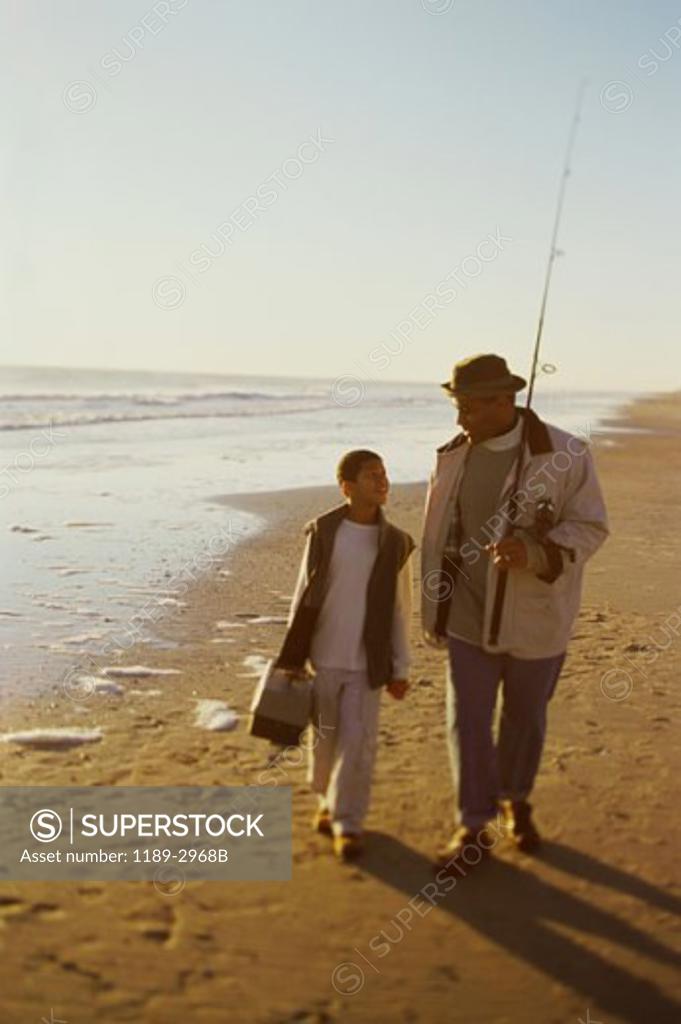 Stock Photo: 1189-2968B Mid adult man walking with his son and holding a fishing pole