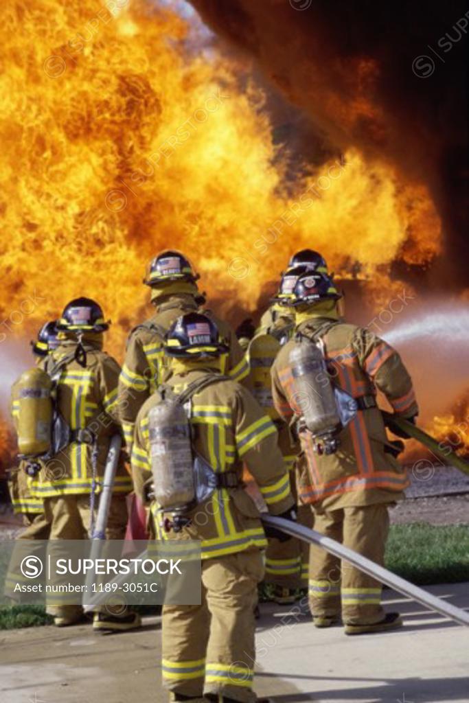 Stock Photo: 1189-3051C Rear view of a group of firefighters extinguishing a fire