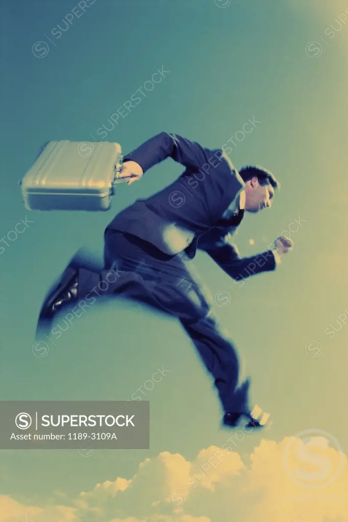 Low angle view of a businessman holding a briefcase in mid-air