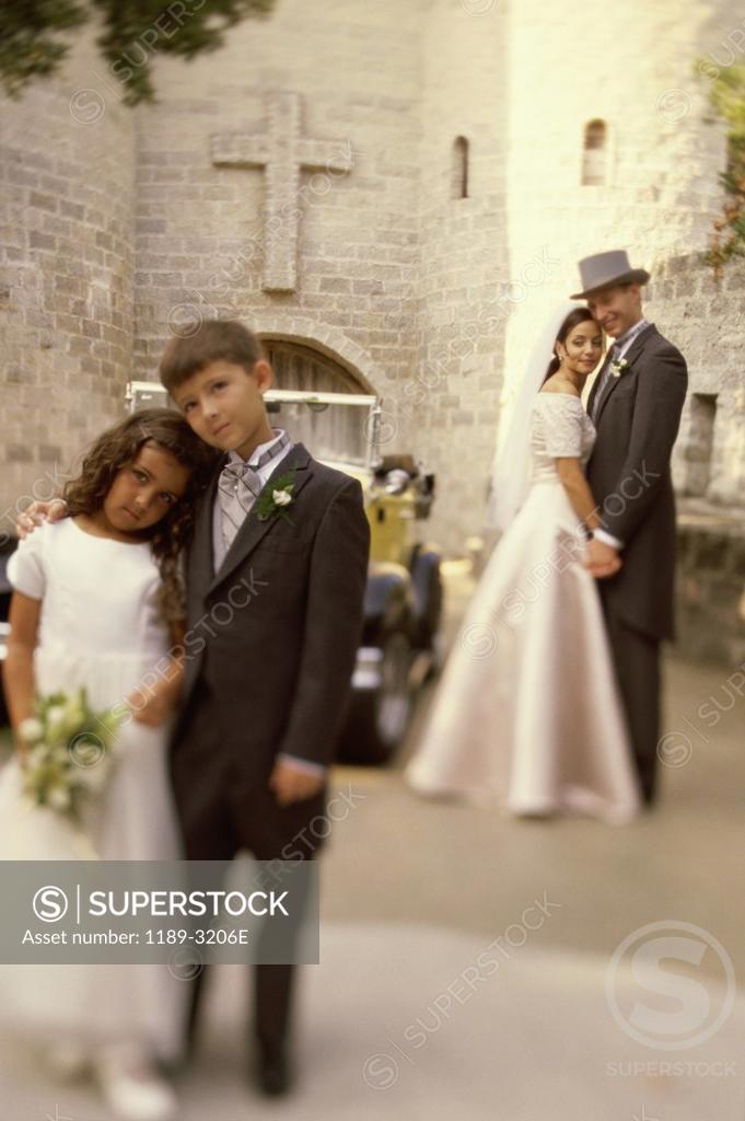 Stock Photo: 1189-3206E Ring bearer and a flower girl standing in front of a newlywed couple
