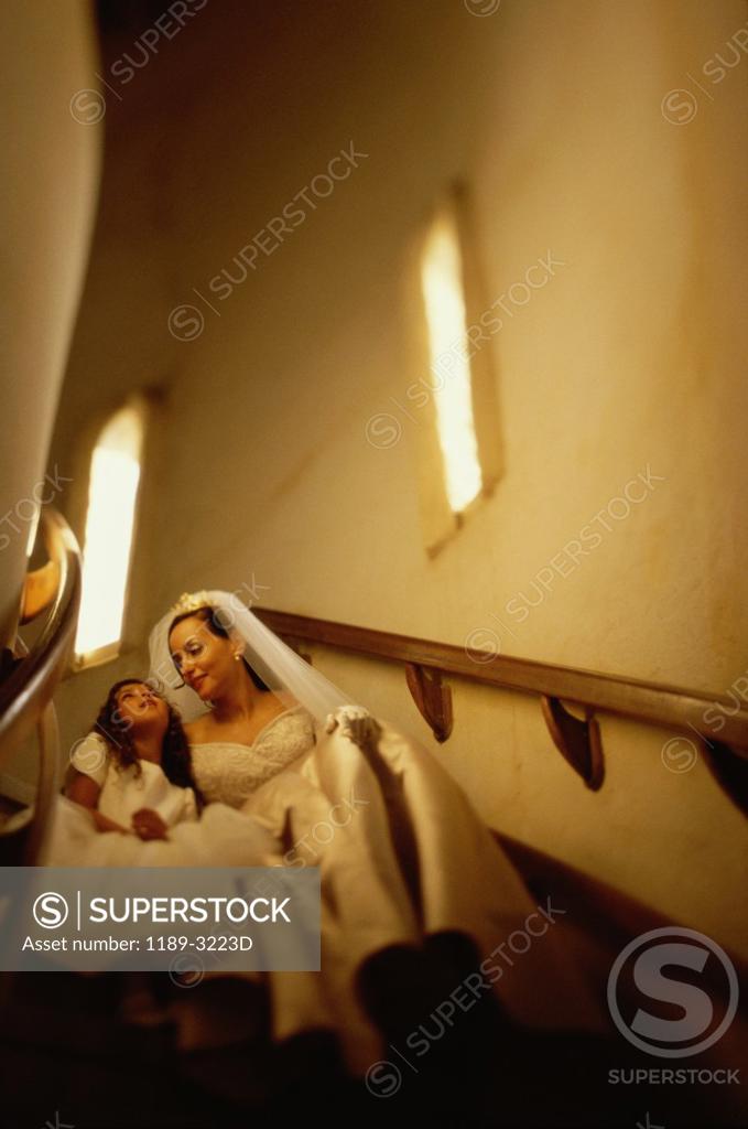 Stock Photo: 1189-3223D Low angle view of a bride sitting with a flower girl on a staircase