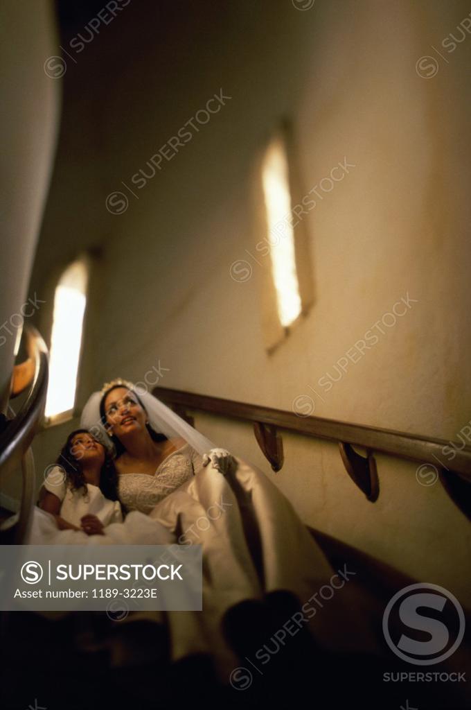 Stock Photo: 1189-3223E Low angle view of a bride sitting with a flower girl on a staircase