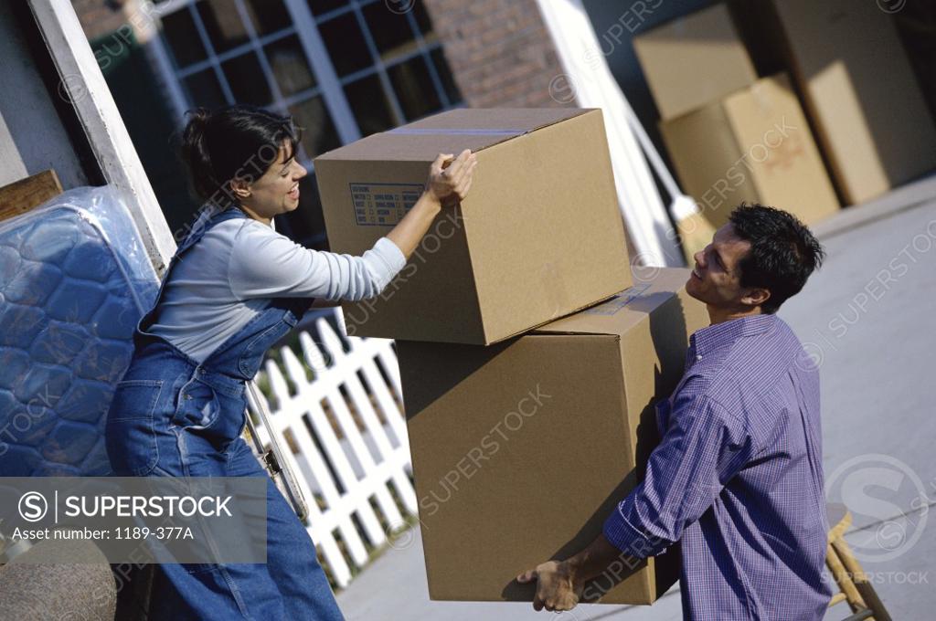 Stock Photo: 1189-377A Young couple unloading cardboard boxes from a moving van