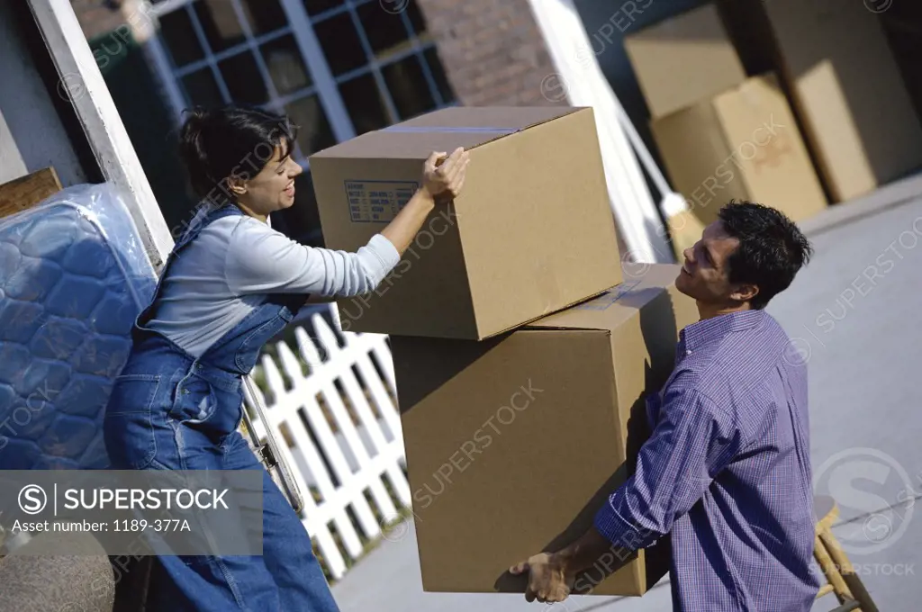 Young couple unloading cardboard boxes from a moving van