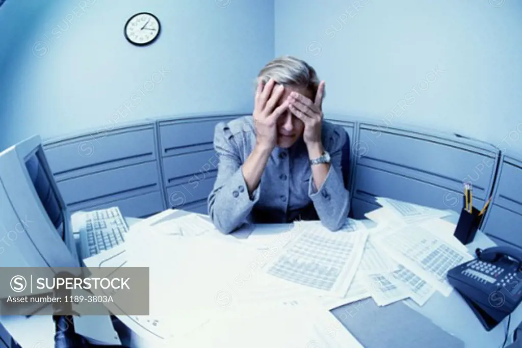 Businesswoman sitting in an office with her head in her hands