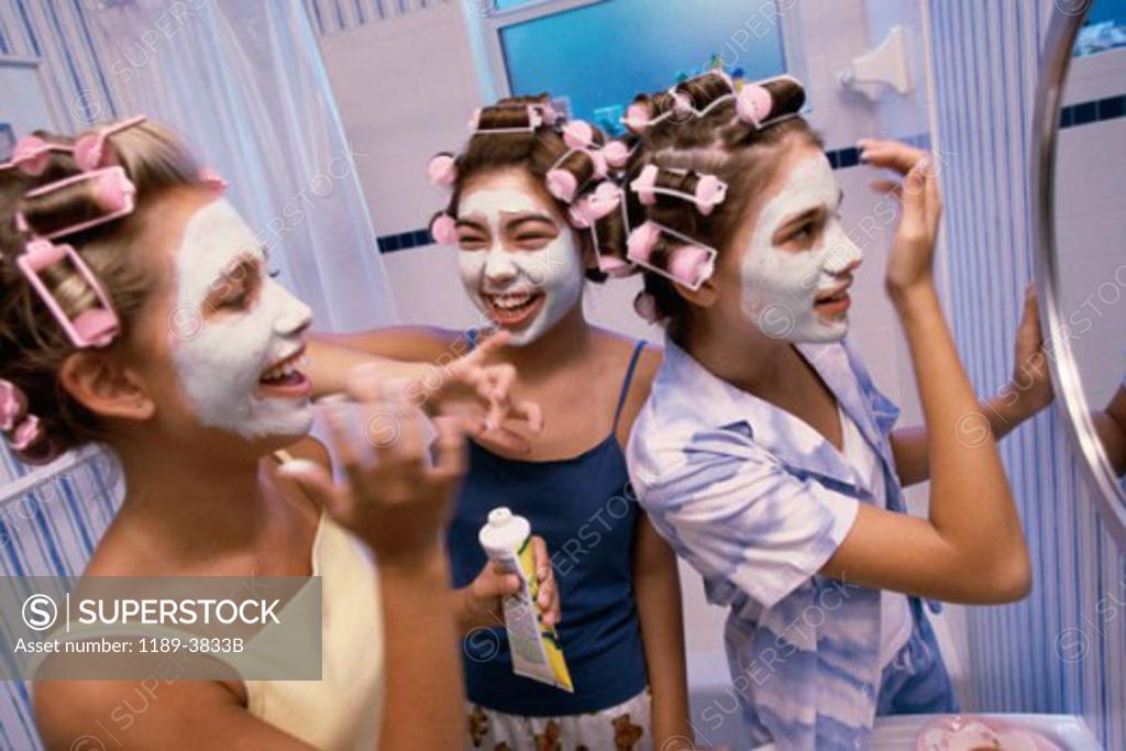Stock Photo: 1189-3833B Three teenage girls applying facial masks to their faces