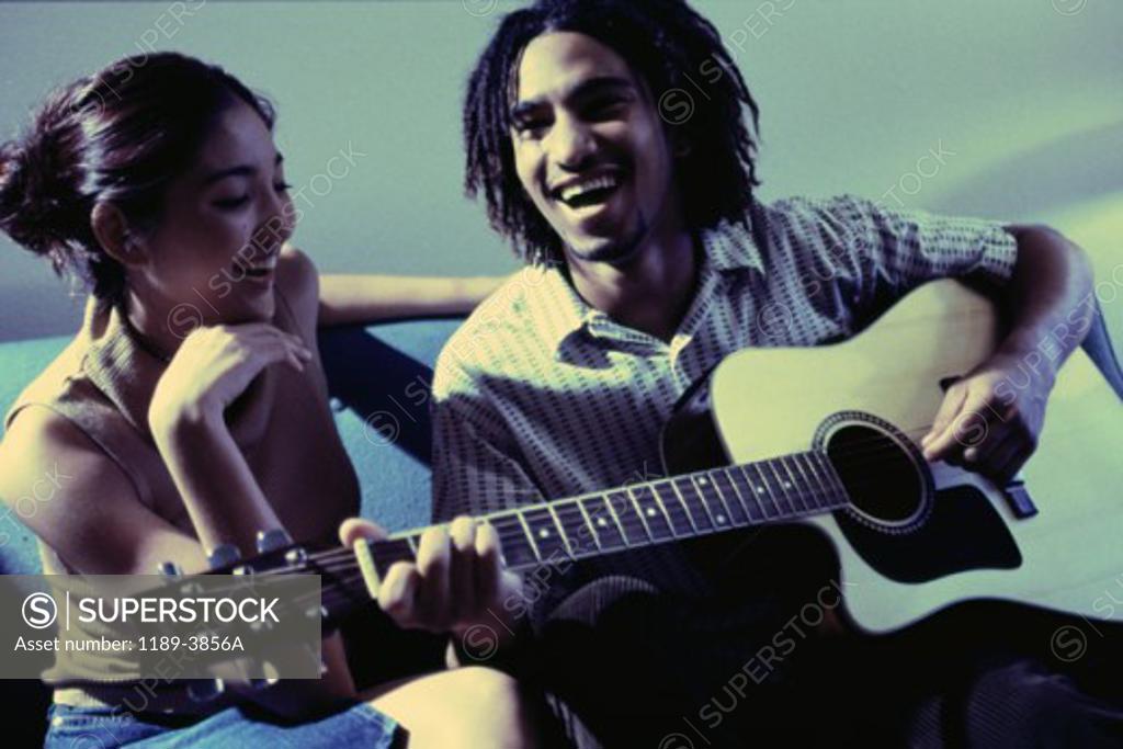 Stock Photo: 1189-3856A Young man playing a guitar with a young woman