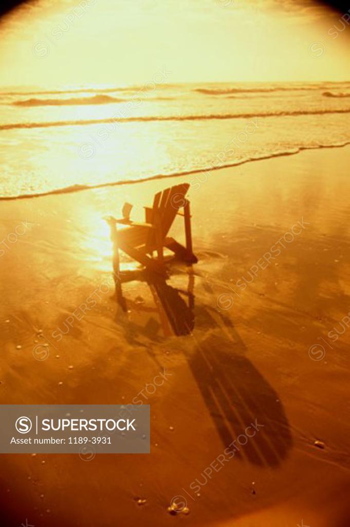 Stock Photo: 1189-3931 A lawn chair on a beach during sunset