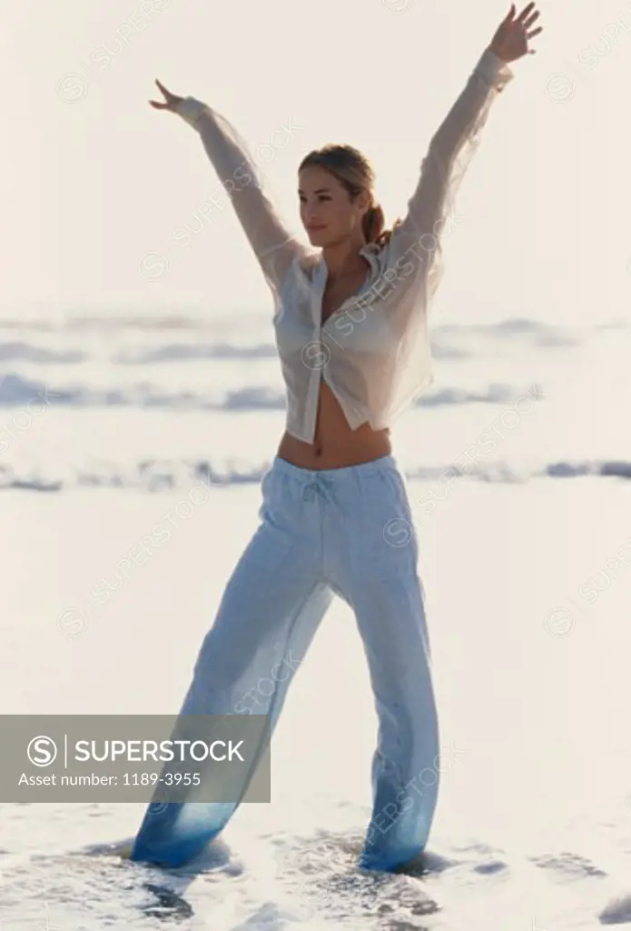 Young woman standing with her arms raised on the beach