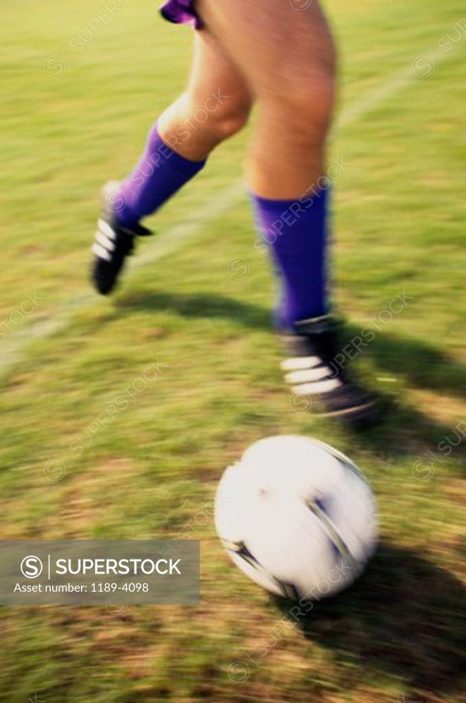 Stock Photo: 1189-4098 Low section view of a soccer player playing with a soccer ball