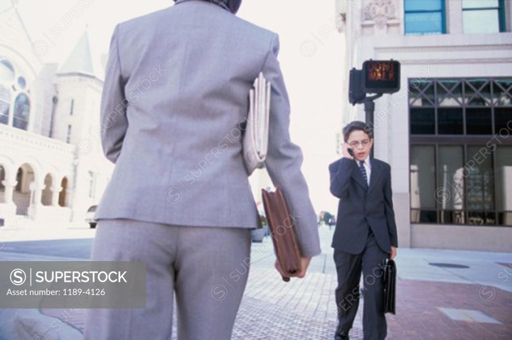 Stock Photo: 1189-4126 Portrait of a boy wearing a business suit talking on a mobile phone