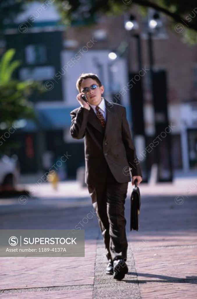 Stock Photo: 1189-4137A Boy wearing a business suit talking on a mobile phone