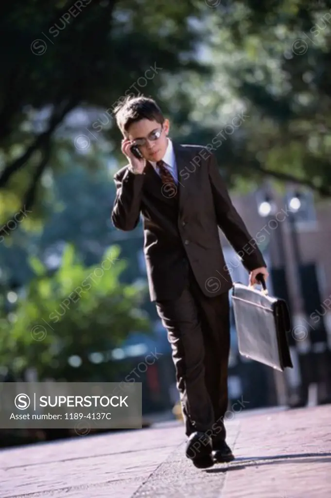 Boy wearing a business suit talking on a mobile phone